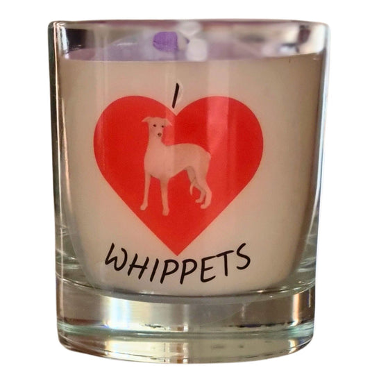 A colourless glass containing white candle wax. On the glass horizontally from the top is I then a large red heart and whippets written underneath. In the heart is a picture of a white and brown whippet dog.