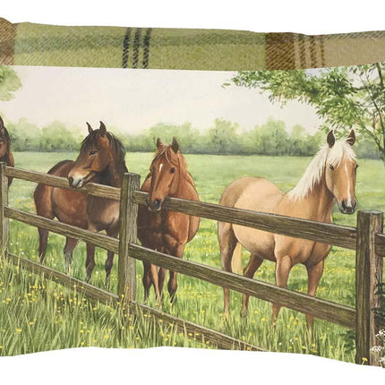 Decorative pillow featuring an illustration of four horses standing by a wooden fence in a grassy field, with trees in the background and a plaid pattern on the pillows edge.