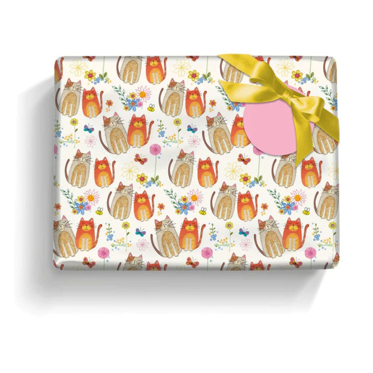 A gift box wrapped in paper decorated with colorful cats, butterflies, and flowers, topped with a yellow ribbon and a blank pink gift tag.