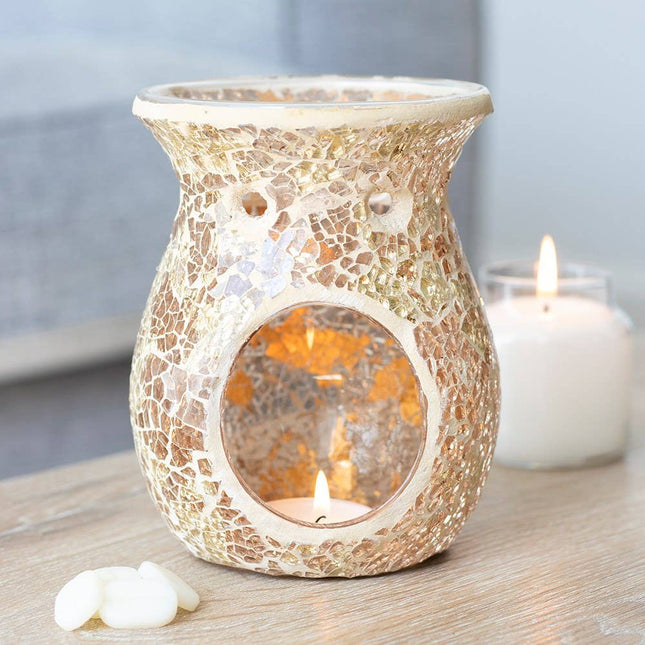 large gold crackle design oil burner wax melt warmer with lit tealight with some wax melts and a burning candle behind