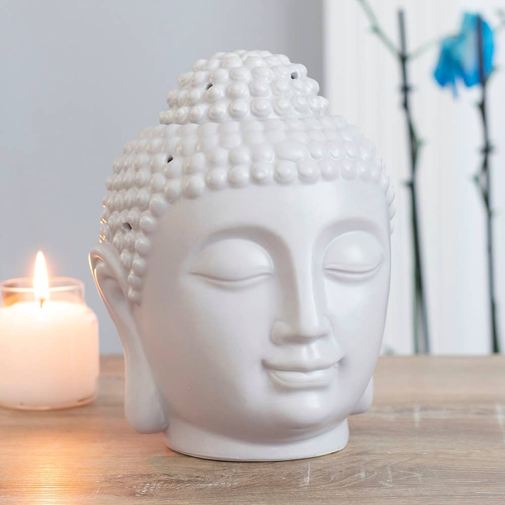 light grey large buddha head wax warmer next to a burning candle