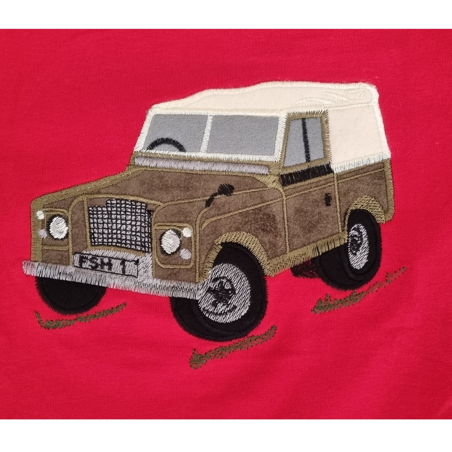 The Ramblers Embroidered T Shirt Farm Vehicle Childrens features a brown vintage off-road farm vehicle with a white roof on red fabric, detailed stitching on wheels, grill, and windowsâ€”ideal for charming any childâ€™s wardrobe.