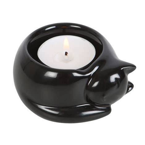 a black glossy tealight holder in the form of a curled up cat with a lit tealight inside