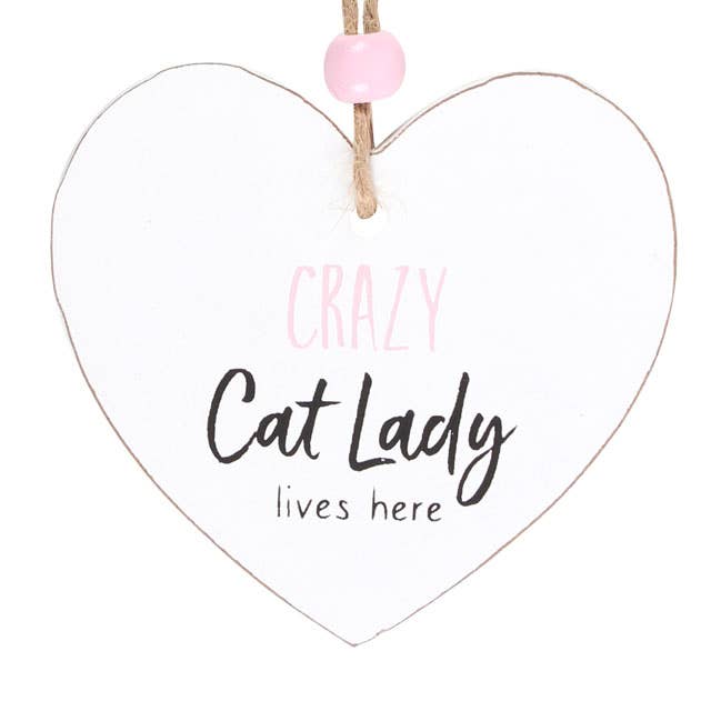 close up of a heart shaped sign which reads crazy cat lady lives here, suspended by a piece of twine and finished with a wooden bead