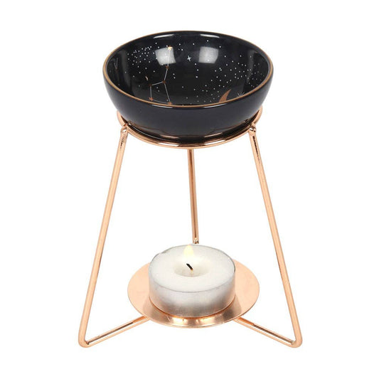 wax warmer with ceramic dish featuring gold celestial accents and a matching gold coloured metal base with lit tealight