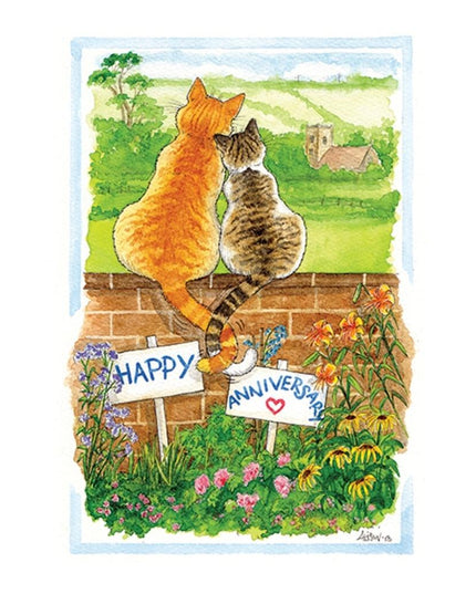 a happy anniversary card featuring a cartoon drawing of two cats sitting on a garden wall looking at the view of a church in the distance. The cats are snuggling up to each other and their tails are entwined