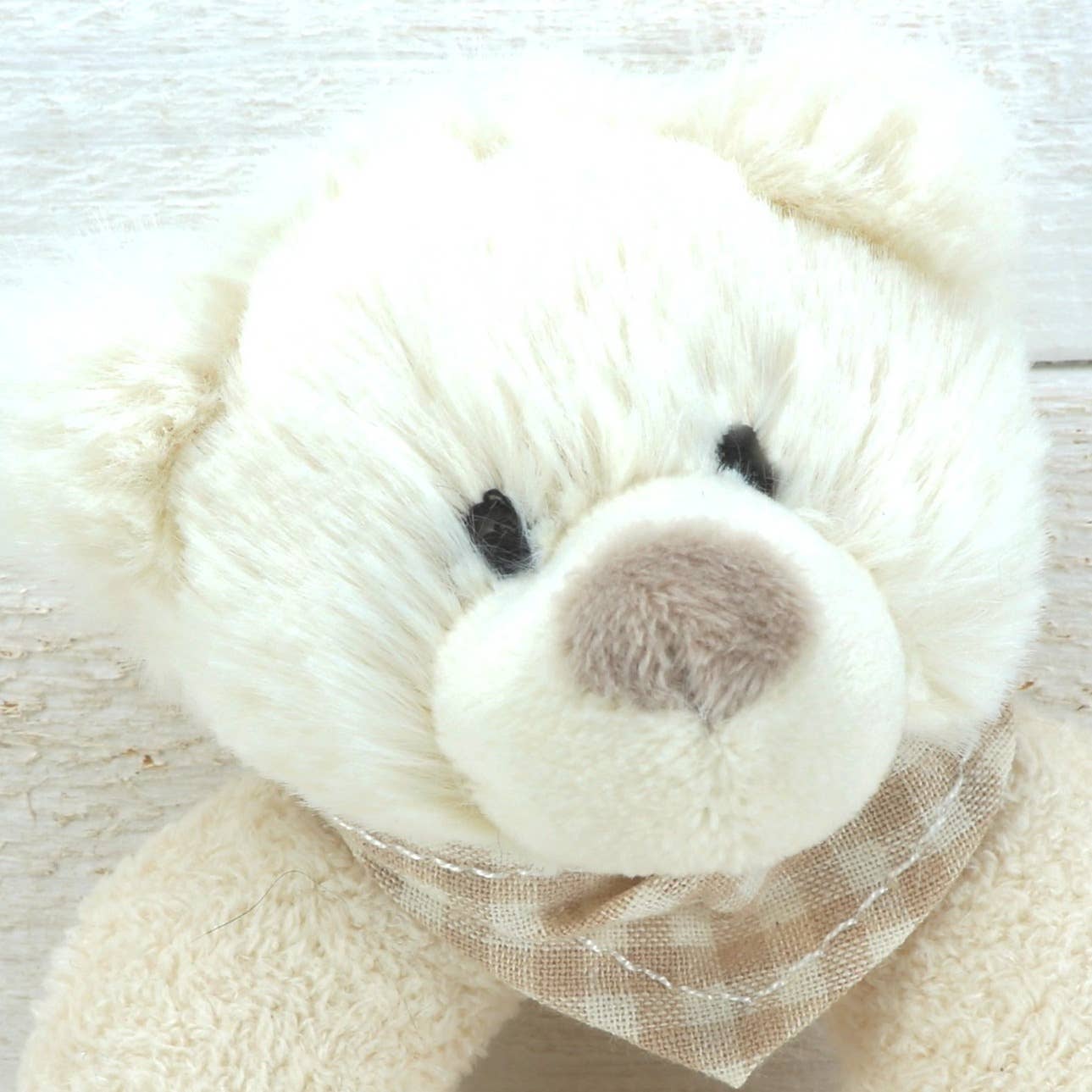 close up of a cream plush rattle with a cute bears head 