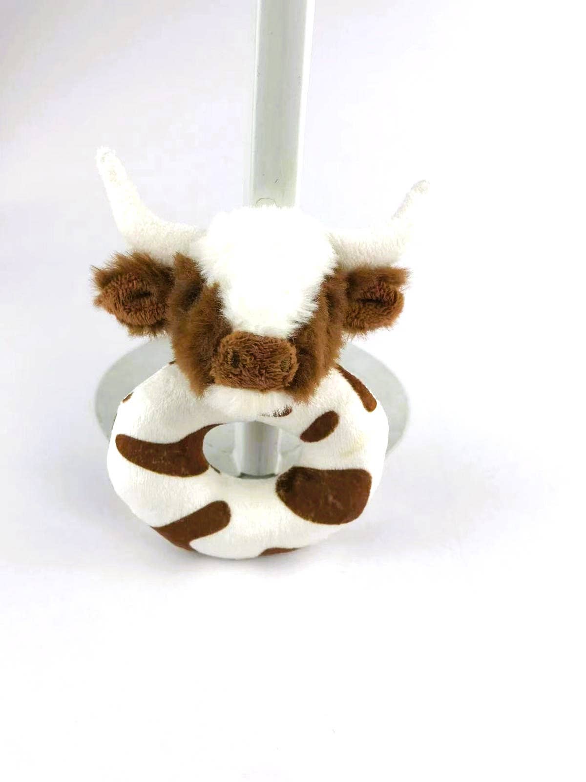 a soft plush circular brown and white baby rattle with a fluffy brown and white longhorn cow head