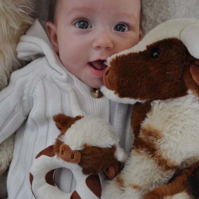 a happy baby with the longhorn baby rattle and large longhorn cow soft toy