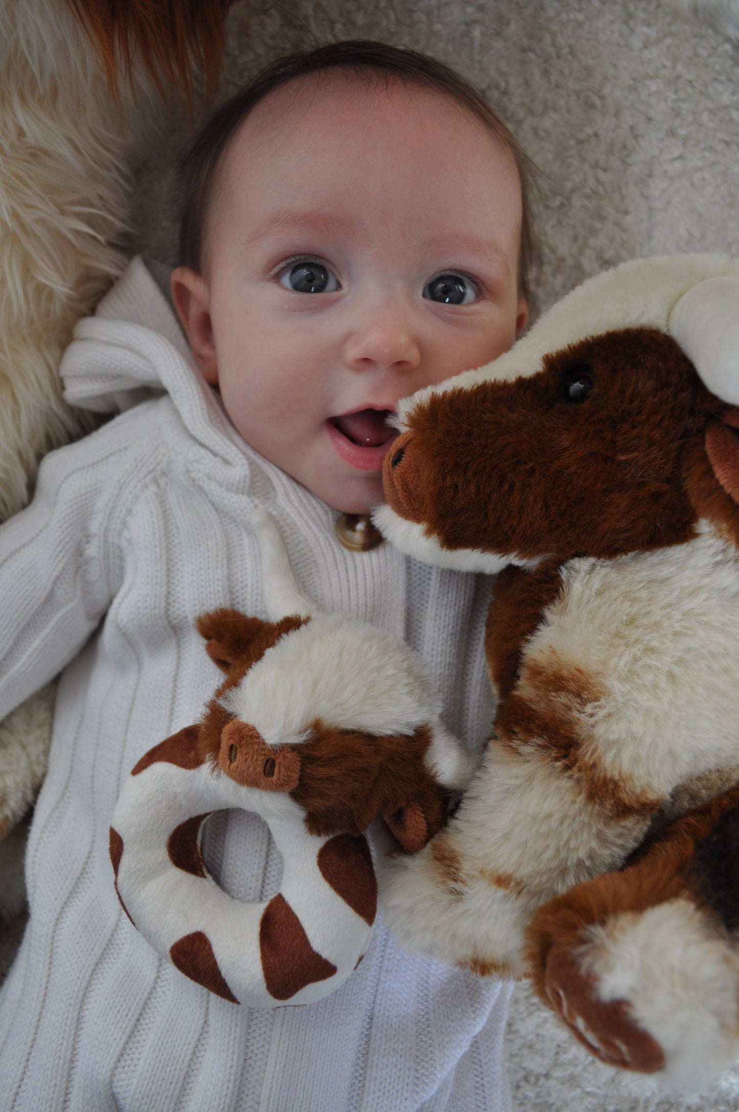 a happy baby with the longhorn baby rattle and large longhorn cow soft toy