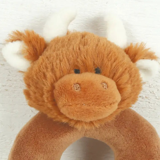close up of a donut shaped new baby rattle in brown soft plush fabric with a cute brown highland cows head with cream horns and ears