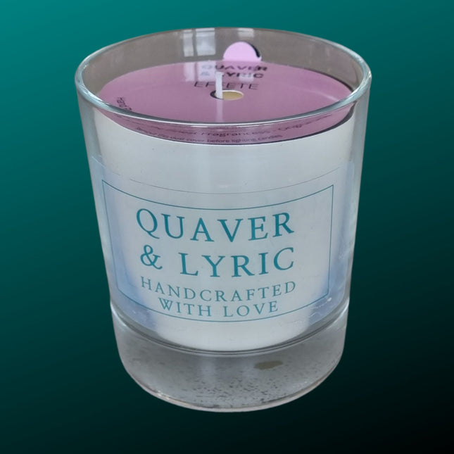 a candle in a glass with quaver & lyric handcrafted with love label and pink dust cover