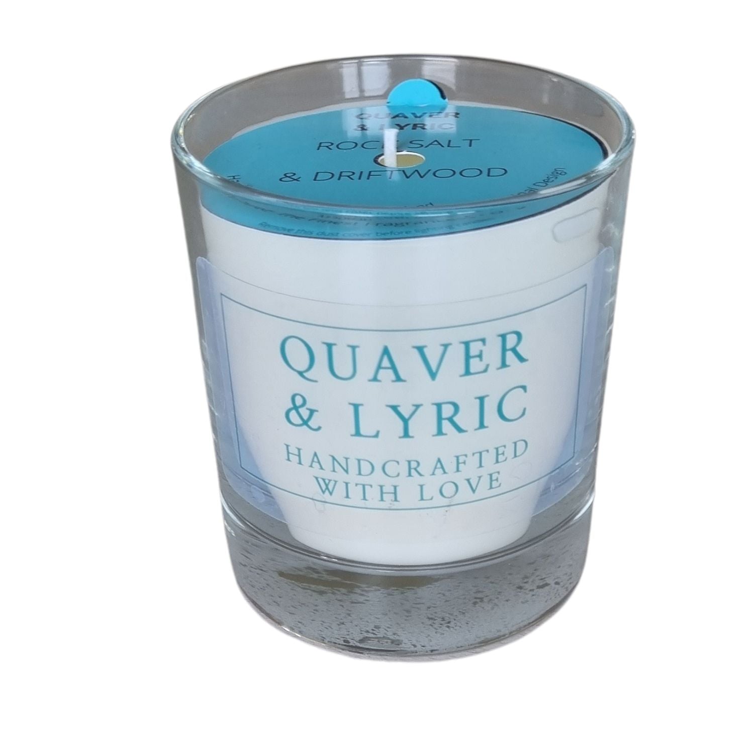 a candle in a glass with quaver & lyric handcrafted with love label and blue dust cover