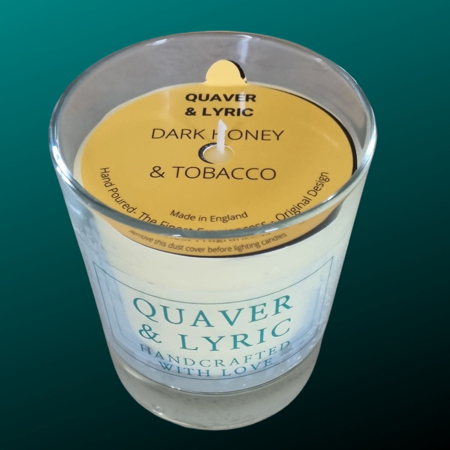 a candle in a glass with quaver & lyric handcrafted with love label and amber dust cover