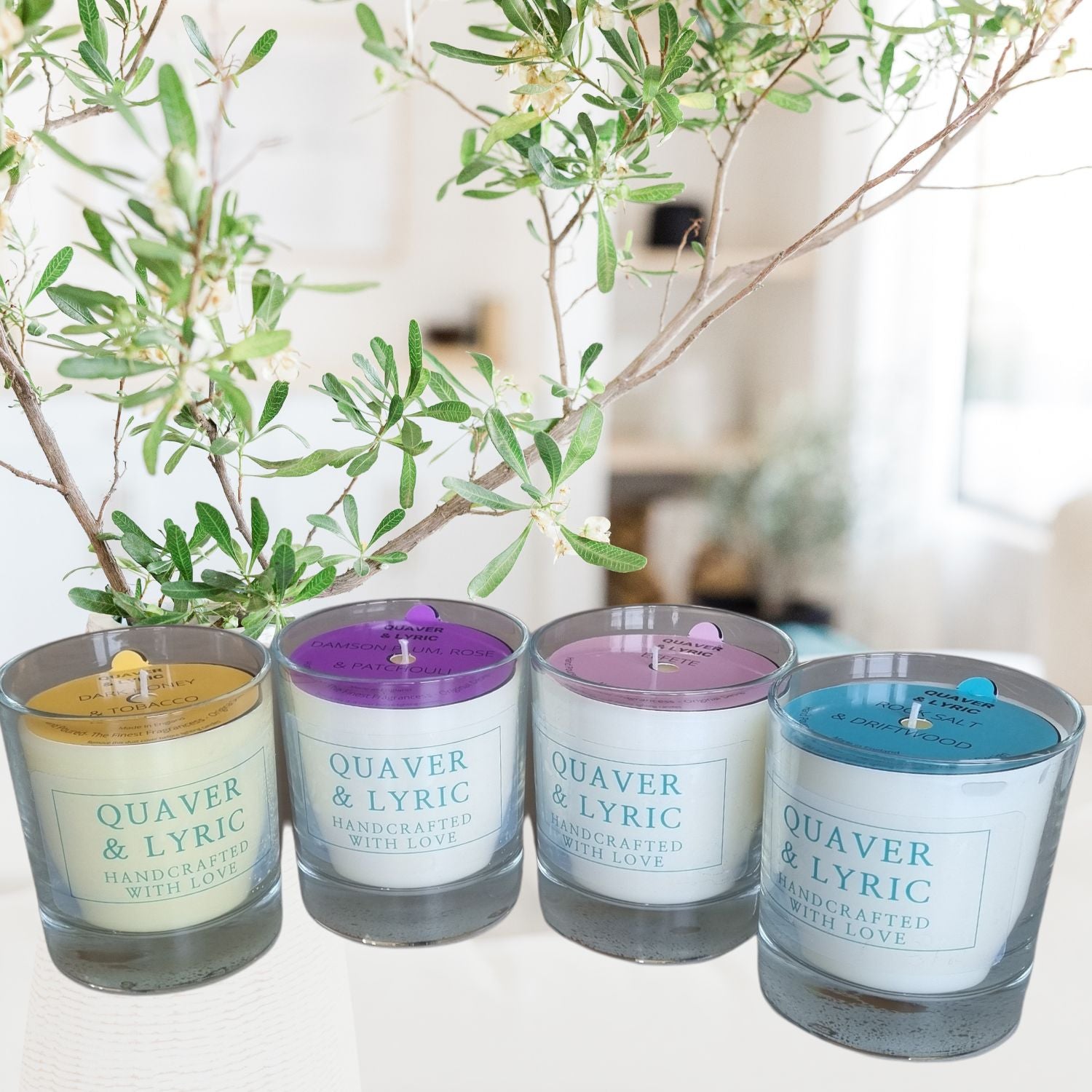a group of four scented candles with quaver and lyric handcrafted with love label in a room setting