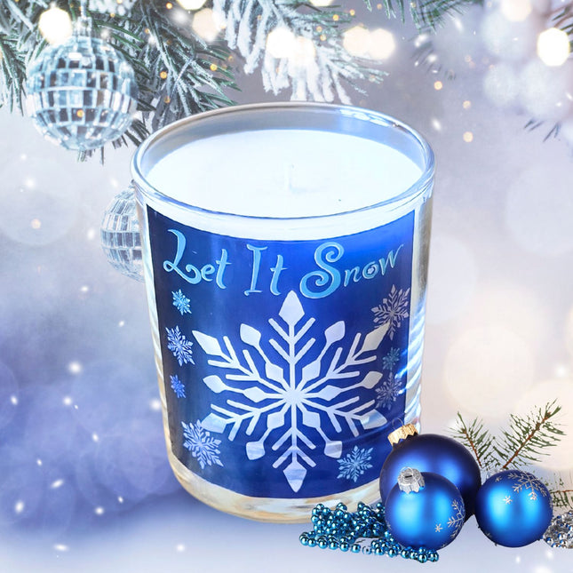 The Quaver&Lyric Christmas Scented Candle in a Let It Snow design glass container sits beside blue ornaments and festive decor, creating a cozy holiday atmosphere.