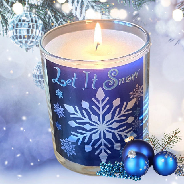 The Quaver&Lyric Christmas Scented Candle in a Let It Snow glass container features a white snowflake design, surrounded by blue ornaments and festive decor with snowy branches for a perfect holiday gift.