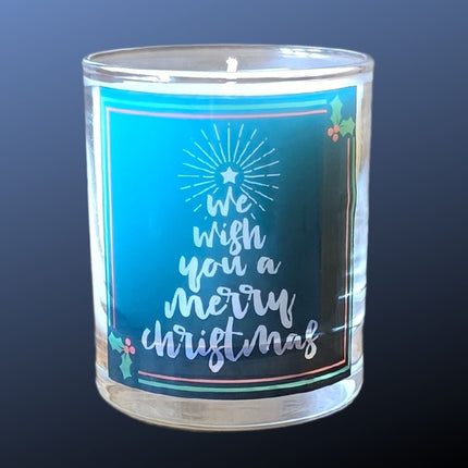 The Quaver&Lyric Christmas Scented Candle comes in a glass container with Wish You A Merry Christmas and holly on a blue background, topped by a tree—perfect festive decor or gift for the holiday season.