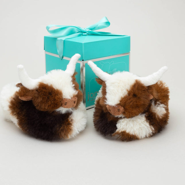 Texas Longhorn Cow Slippers for Infants by Jomanda Soft Toys & Accessories feature adorable brown-and-white cow designs with white hornsâ€”an ideal infant gift with a turquoise, ribbon-tied gift box.