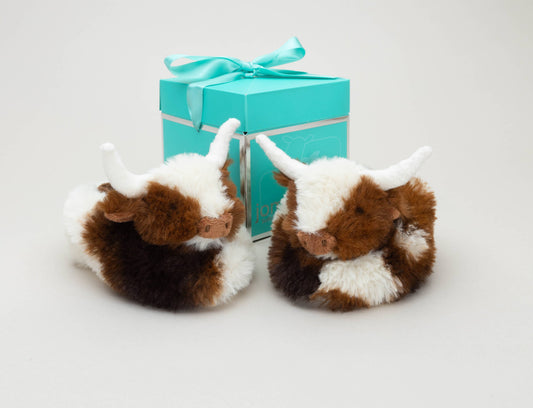 Texas Longhorn Cow Slippers for Infants by Jomanda Soft Toys & Accessories feature adorable brown-and-white cow designs with white horns—an ideal infant gift with a turquoise, ribbon-tied gift box.