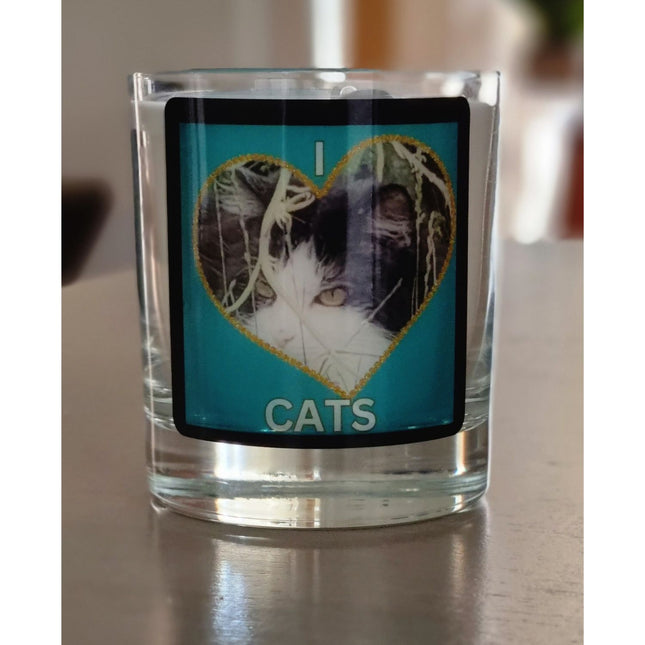 scented candle in glass container with fluffy black and white cat in a heart love cats design on a table