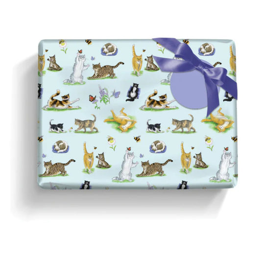 a gft wrapped in paper featuring a variety of adorable cats with flowers, bees and butterflies on a pale blue background with a round lilac gift label