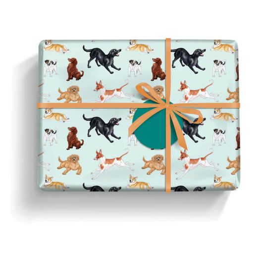 a gift wrapped in paper featuring a variety of adorable energetic dogs on a pale aqua background with a round teal gift label