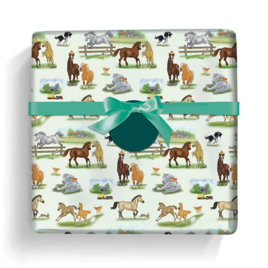 a gift wrapped in paper featuring a variety of lively cheeky ponies and horses on a pale  background with a round green gift label