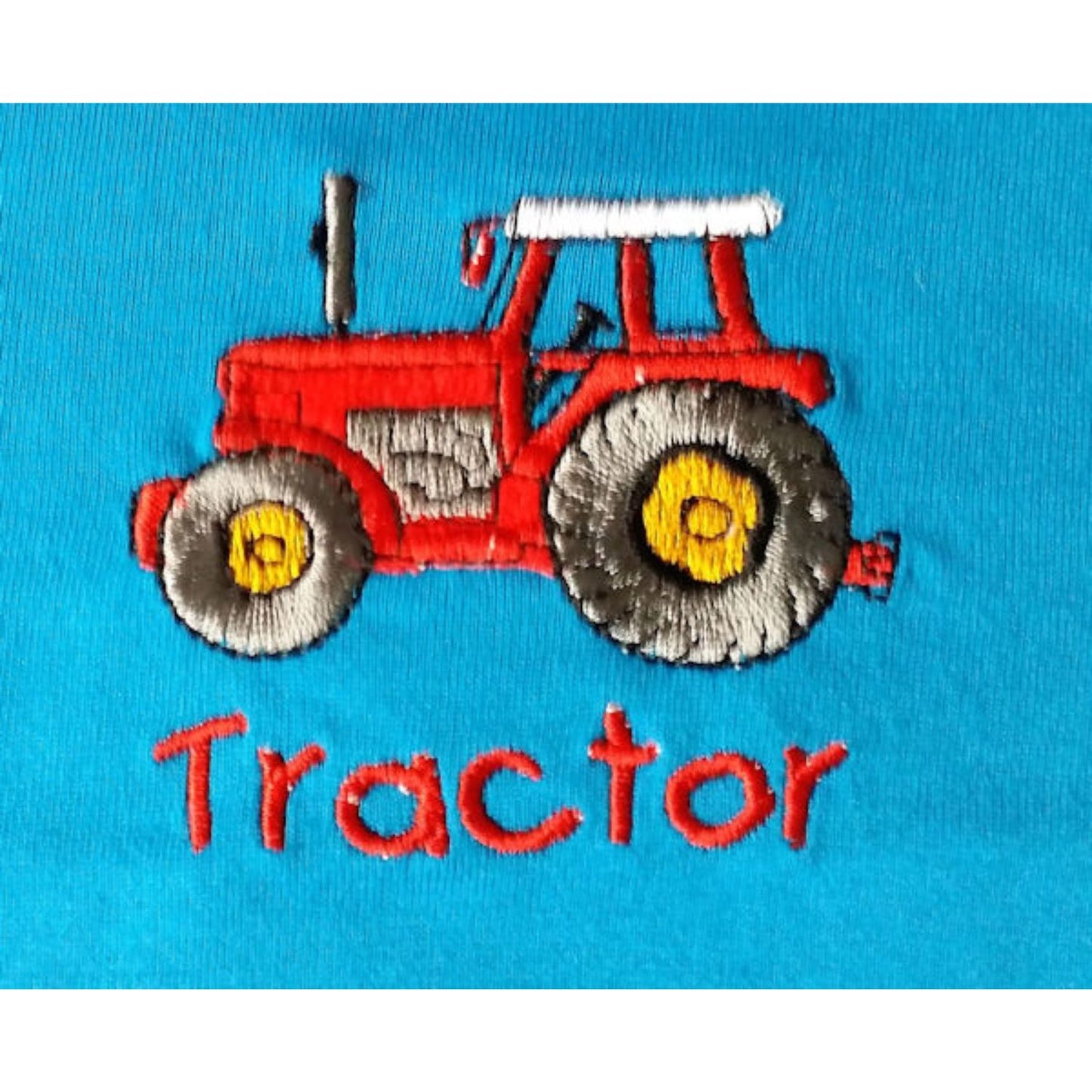 The British Country Collection Infant T Shirt Embroidered Tractor Blue features a red tractor with yellow wheels stitched on blue 100% cotton and Tractor in red below; its machine-washable, cute, and comfy for infants.