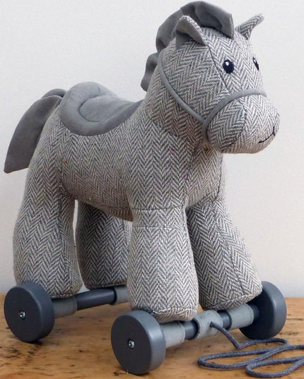 life style shot an adorable grey cuddly pony pull along toy made from herringbone fabric on detachable wheels with textured mane and tail. Made by Little Bird Told Me