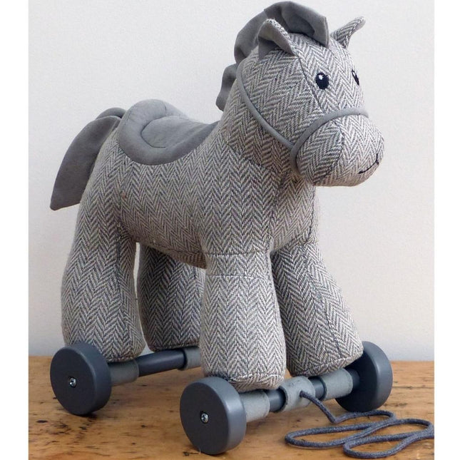 life style shot an adorable grey cuddly pony pull along toy made from herringbone fabric on detachable wheels with textured mane and tail. Made by Little Bird Told Me