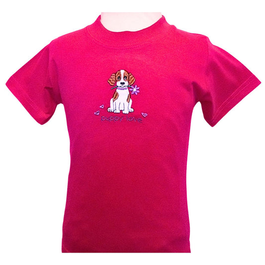 Short sleeve, round necked fuchsia pink T-shirt featuring a brown and white embroidered puppy who has a flower in his mouth. Underneath is written puppy love