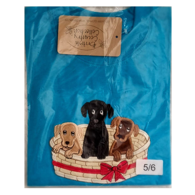 The British Country Collection Dog T Shirt Embroidered Basket of Puppies Design for children features three embroidered puppies in a basket with a red bow, folded in plastic packaging and labeled size 5/6.