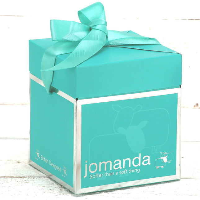 A turquoise 10cm Jomanda Pop-Up Gift Box for mini toys or slippers, with ribbon, sheep illustrations, and the slogan Softer than a soft thing by Jomanda Soft Toys & Accessories, sits on a white wooden surface.