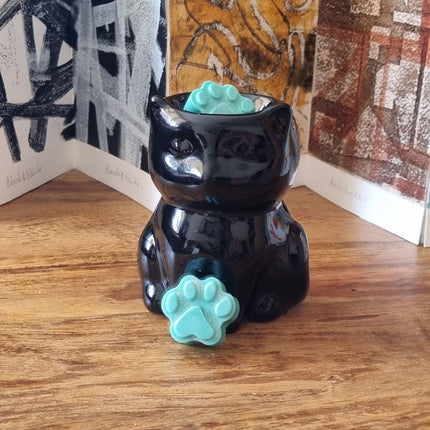 a black cat waxwarmer with green paw shaped wax melts