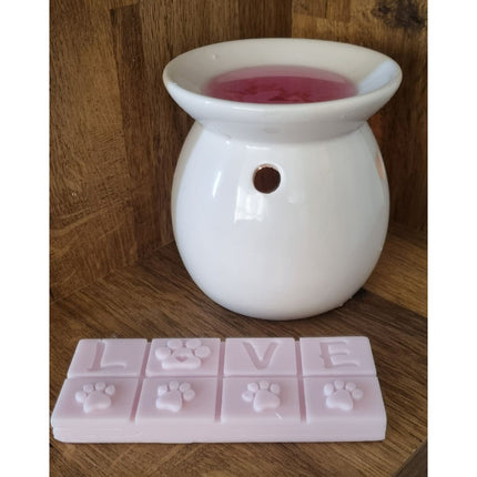 A Quaver&Lyric Highly Scented Wax Melt Bar in a two-tone Love Paws design sits on a wooden surface—perfect as a gift for pet lovers. The pink bar spells “LOVE,” with paw prints replacing the O, and pairs with your favorite wax warmer.