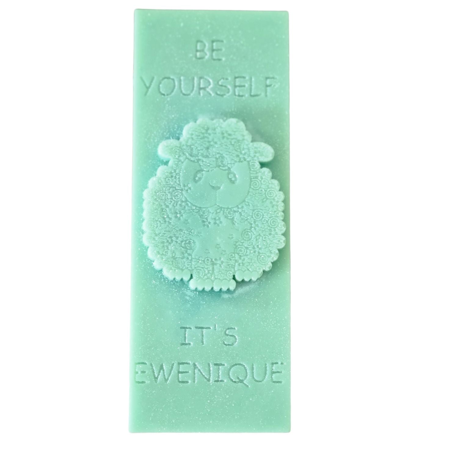 A light green coloured rectangle of wax with a raised sheep design with the writing be yourself above and it's ewenique below.