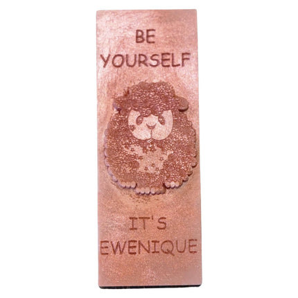 A bronze coloured wax melt bar with a raised sheep design with the writing be yourself above and it's ewenique below.