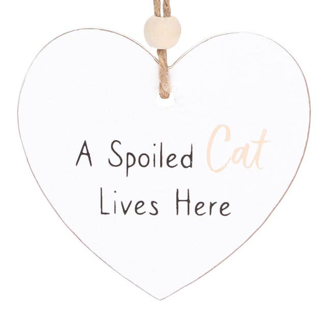 close up of a heart shaped sign which reads a spoilt cat lives here, suspended by a piece of twine and finished with a wooden bead