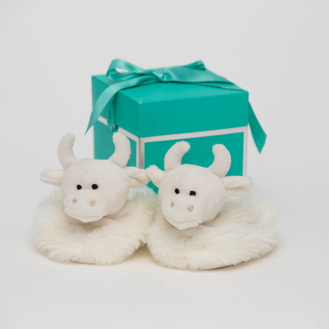 A pair of fluffy white baby cow-face slippers sits in front of a Jomanda Soft Toys & Accessories Gift Box Pop-Up (10cm), suitable for mini toys or slippers, displayed on a white background with a teal ribbon.