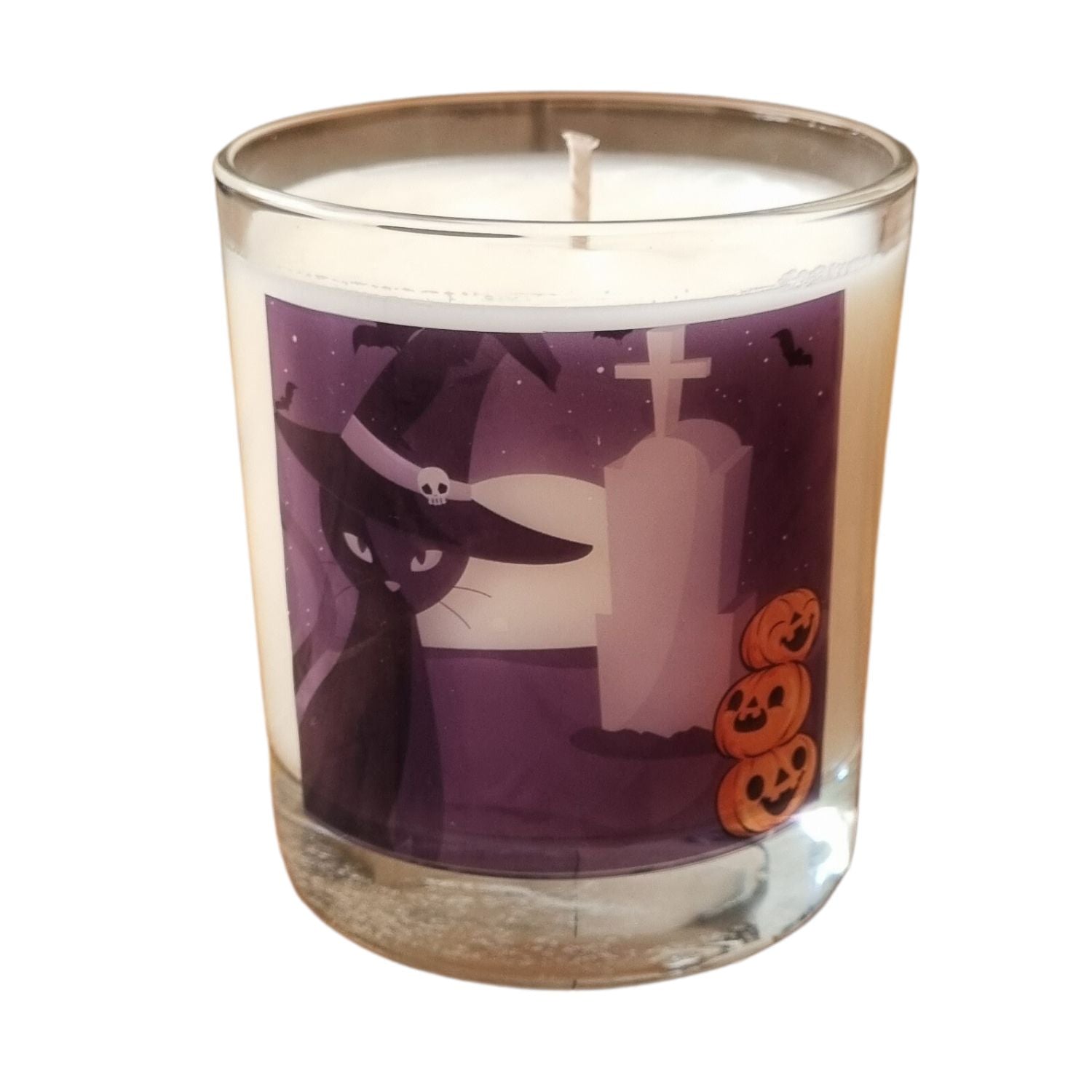 glass container halloween candle with black cat in witches hat in a graveyard with pumpkins