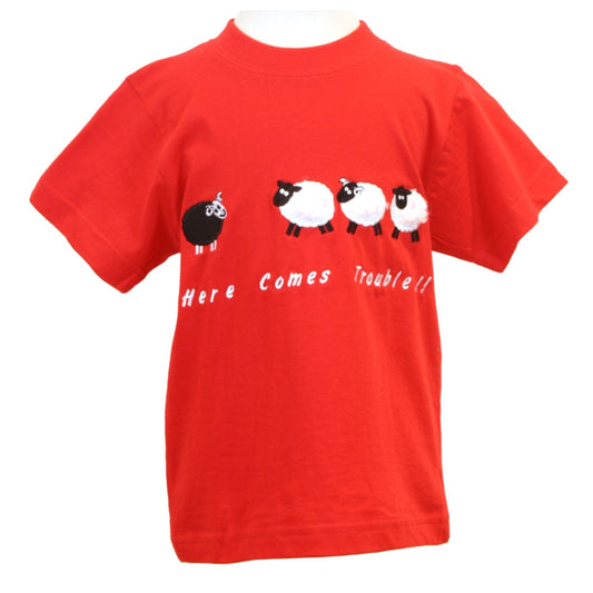 red short sleeve round neck t shirt with one black sheep looking towards three white sheep. Underneath is written here comes trouble