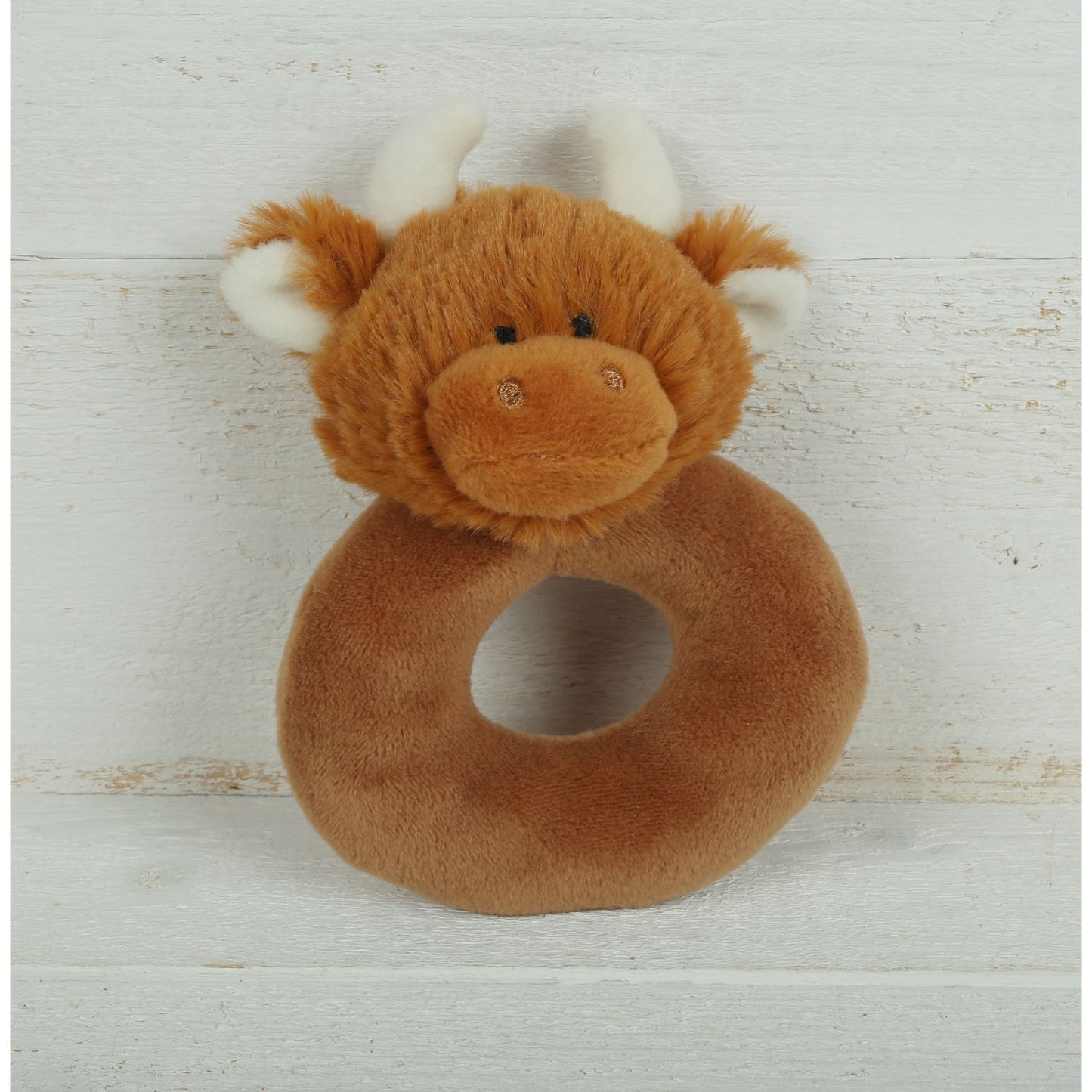 a donut shaped new baby rattle in brown soft plush fabric with a cute brown highland cows head with cream horns and ears