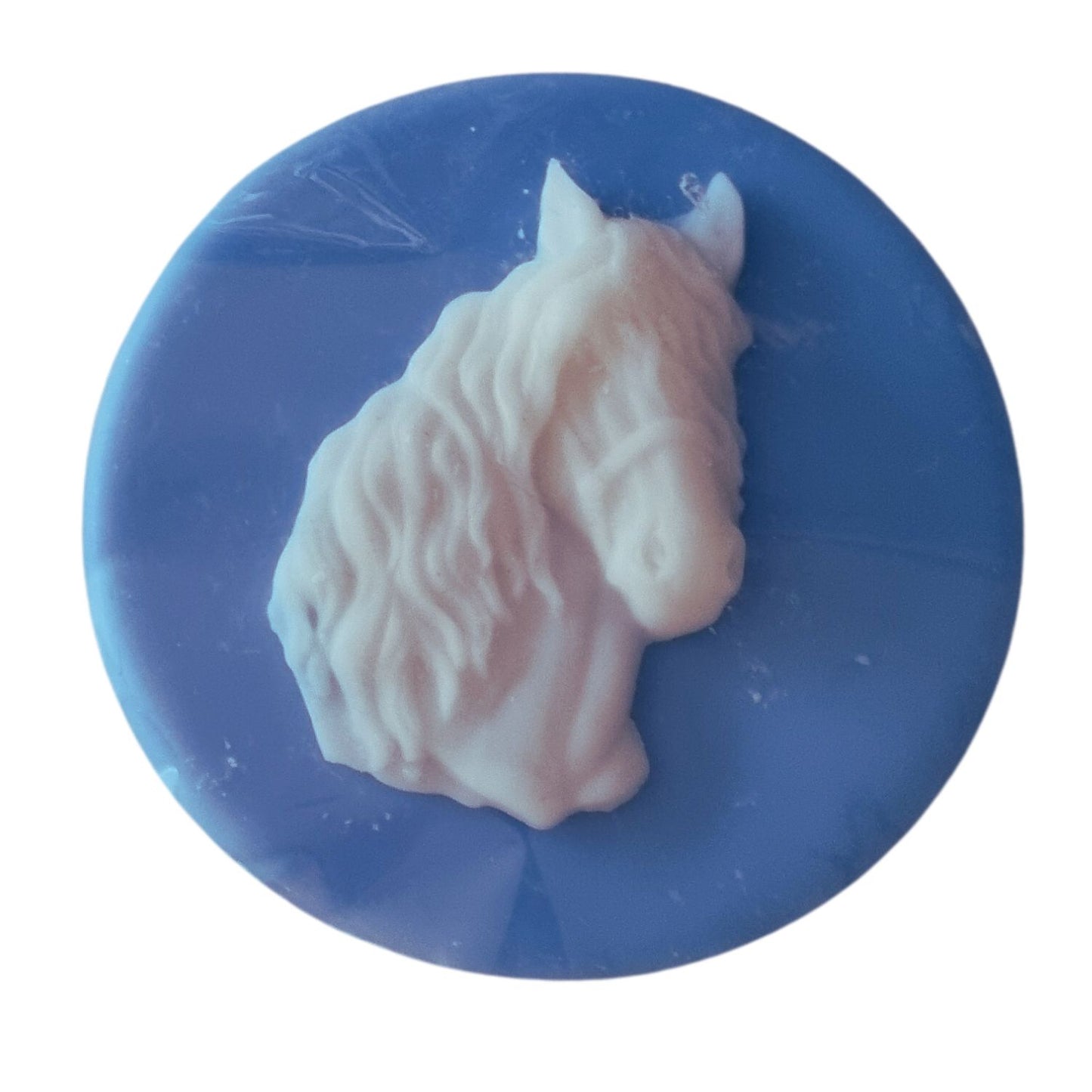 A blue coloured disc shaped wax melt with a white wax horses head with a flowing mane and forelock.