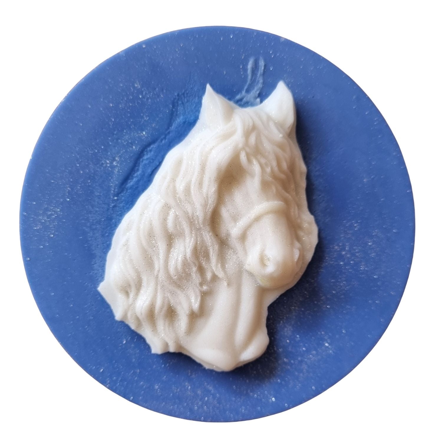 An ocean blue coloured disc shaped wax melt with a white wax horses head with a flowing mane and forelock.