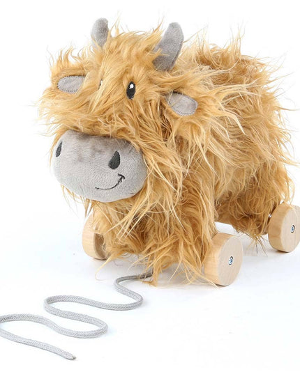 a cute highland cow stuffed toy with golden fur on wooden wheels