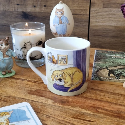 The Alisons Animals Cat and Dog Mug I Do Own The Place, featuring charming artwork, sits on a wooden table with cat-themed decor like a candle, figurine, painted egg, and illustrated cards. Gift boxed for the perfect present.