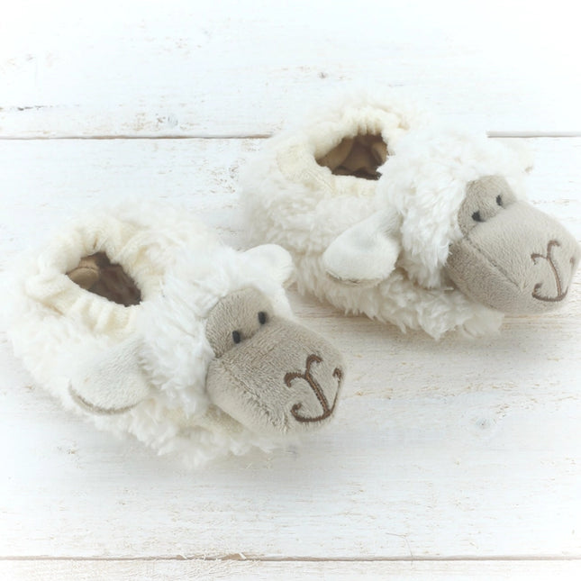 A pair of light cream fluffy baby boots with cute embroidered faces
