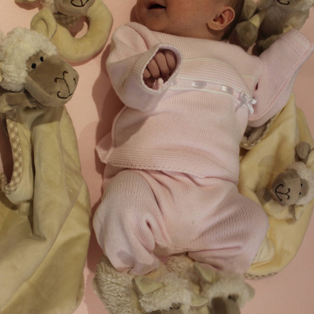 a giggling baby surrounded by a range of plush cream sheep baby toys