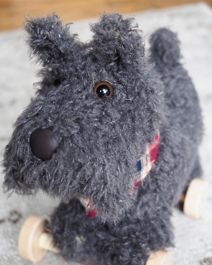 close up of soft toy pull along scottie dog with grey fur and a plaid neckerchief